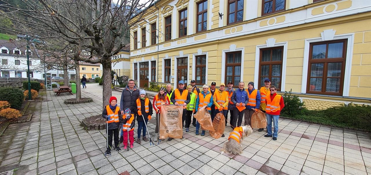Gruppe von Helferinnen und Helfern in Warnwesten und mit Müllsäcken in den Händen