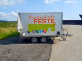 Seitliche Ansicht eines Spezialanhängers, dem Geschirrmobil mit Aufdruck "Sauberhafte Feste"