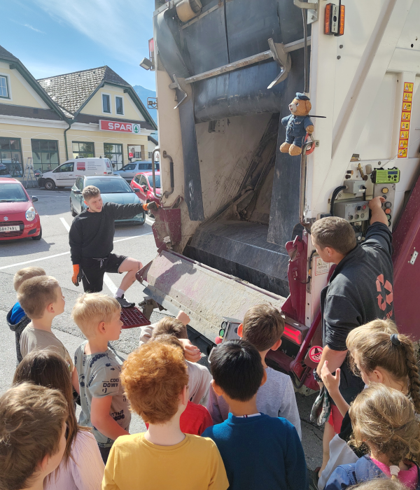 Kinder stehen vor der r&uuml;ckseitigen &Ouml;ffnung eines M&uuml;llfahrzeugs