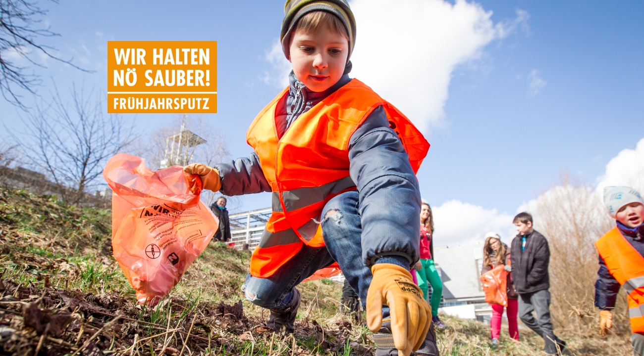 Junge mit Warnweste greift nach achtlos weggeworfenem Gegenstand. Er hält einen Müllsack in der Hand. Im Hintergrund sind weitere Kinder zu sehen.