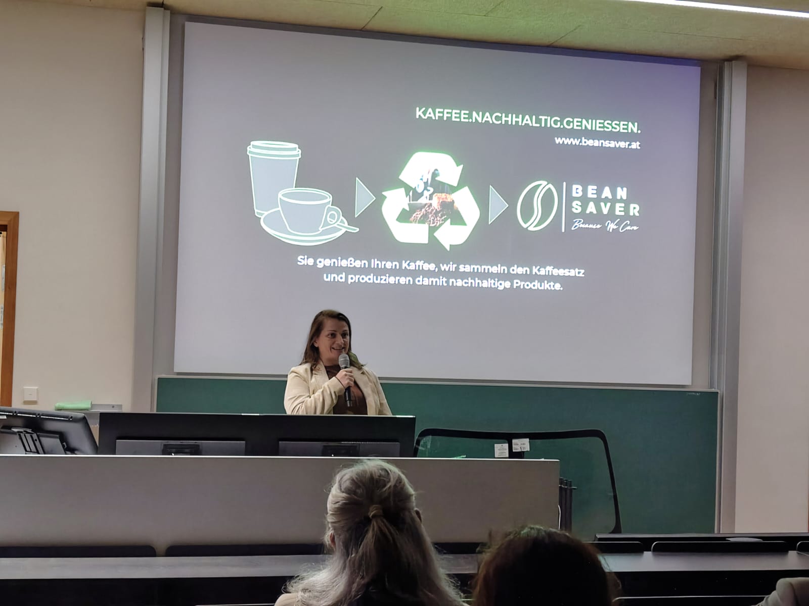 Frau mit Mikrofon steht vor Leinwand
