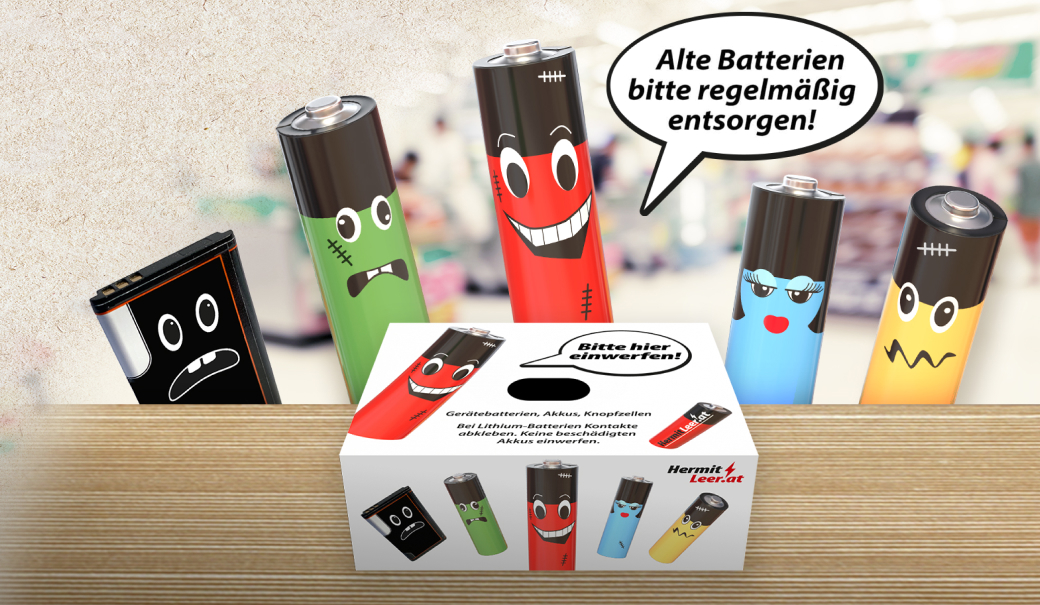 Verschiedene Batterien mit aufgemalten Gesichtern hinter einer Tischplatte und die Batterie-Sammelbox "Hermit Leer"